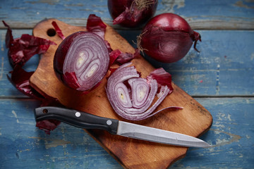Red Onion Slices on wooden board with dark background 