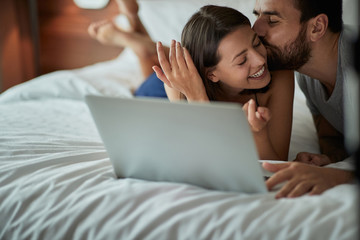 Happy in bed – couple enjoying and kissing in the bed.