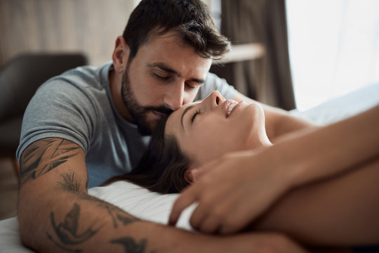 Sexy men and woman being intimate in bed.