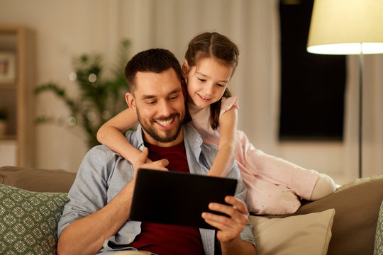 Family, Fatherhood And Technology Concept - Happy Father And Little Daughter With Tablet Pc Computer At Home In Evening