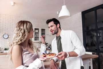 Dark-haired bearded man in a white shirt and his wife enjoying breakfast