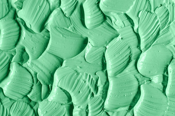 Fototapeta na wymiar Green cosmetic clay (facial mask, cream, body scrub) texture close up, selective focus. Abstract background with brush strokes.