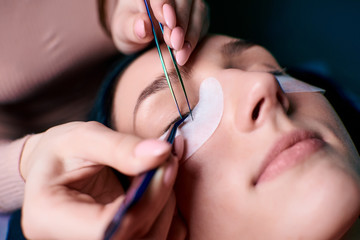 Eyelash extension procedure close up. Beautiful Woman with long lashes in a beauty salon.