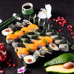 Sushi rolls set served on black stone slate on dark background