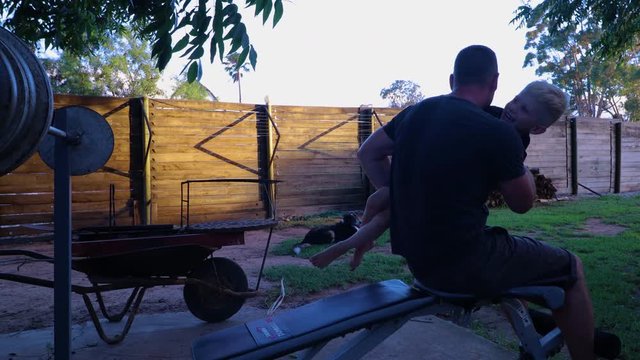 Father and son exercising together in a playful way while both are smiling and laughing