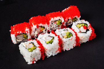 Sushi rolls set served on black stone slate on dark background