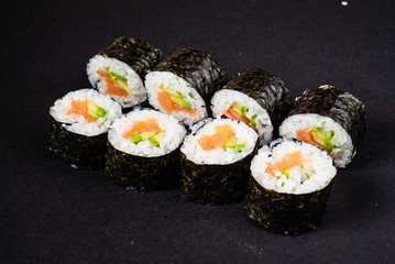 Sushi rolls set served on black stone slate on dark background