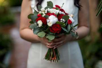 bride in a white wedding dress holding a beautiful bouquet of roses and cotton