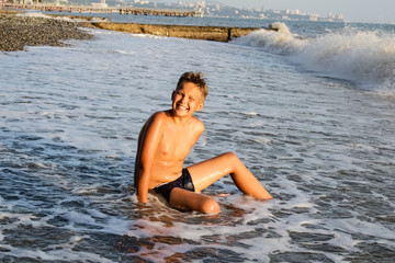 Cheerful boy sitting on the beach