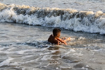Fototapeta premium boy teenager lies on the seashore his washes sea foam and waves