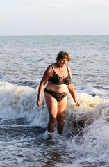 Fototapeta premium Woman in a swimsuit bathes in the sea, big waves