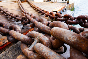 Close up of old rusty chain, industrial port with chainss, crane background out of focus, sunny day, industrial concept