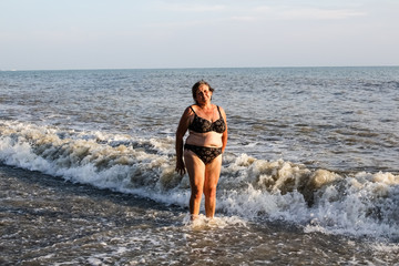 Woman in a swimsuit bathes in the sea, big waves