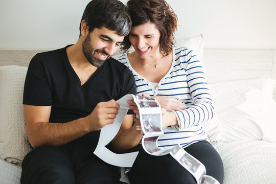 Happy pregnant couple looking at the ultrasound images of their baby