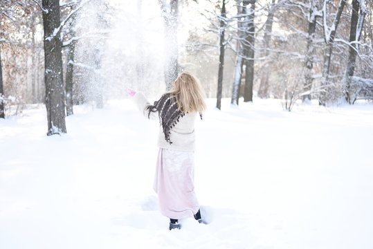 Cheerful girl in the winter forest is having fun in the falling snow.
