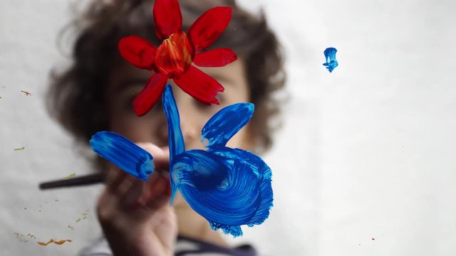Sweet little boy is painting on transparent glass. 4K