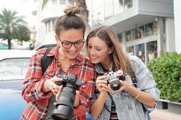 Young smiling photography students taking photos outdoors in urban setting