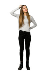 Full-length shot of young girl having doubts while scratching head on isolated white background