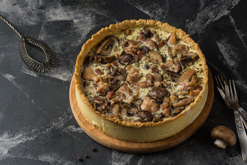 Mushroom Quiche Pie with champignons and cheese on dark background, top view. Savory tart with mushrooms. Galette. Tart with chicken. Chicken pie. Mushroom pie.