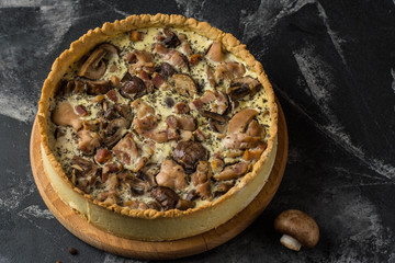Mushroom Quiche Pie with champignons and cheese on dark background, top view. Savory tart with mushrooms. Galette. Tart with chicken. Chicken pie. Mushroom pie.