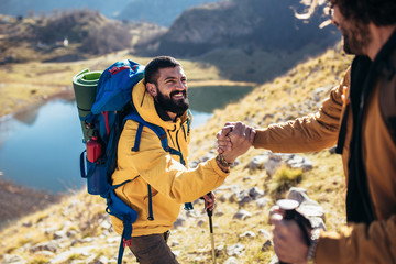 Helping hand - hiker man getting help on hike happy overcoming obstacle.