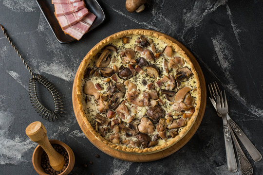 Mushroom Quiche Pie with champignons and cheese on dark background, top view. Savory tart with mushrooms. Galette. Tart with chicken. Chicken pie. Mushroom pie.
