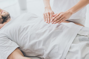 cropped shot of bearded man receiving reiki treatment on stomach