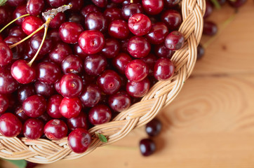 Ripe juicy cherries in basket on a wooden background.