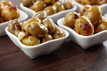 Spiced green olives in oil on a wooden table.