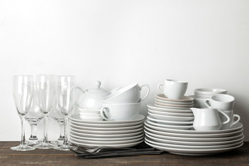A stack of dishes. tableware on a brown wooden table. dishes for serving the table. plates and cutlery, cups and teapot, glasses. with space for text
