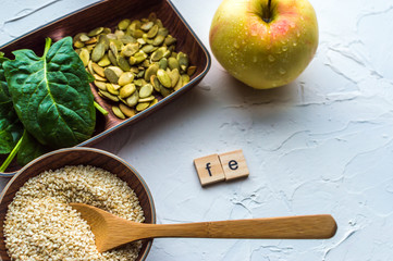 Spinach, pumpkin seeds, sesame, apple and one wood spoon on a white background. microelement FE....