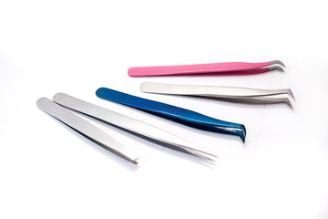 Five tweezers for eyelash extension and eyebrow correction in different colors isolated on white...