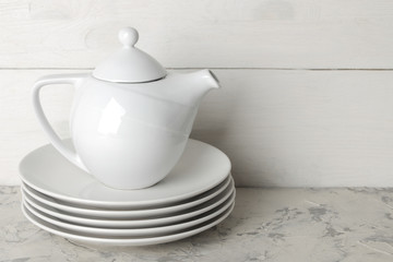 A stack of dishes. tableware on a light concrete background. dishes for serving the table. white plates and kettle