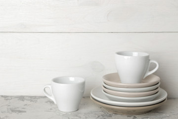 A stack of dishes. tableware on a light concrete background. dishes for serving the table. white plates and cups