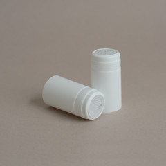 Two white plastic caps for wine bottles on a gray background. Caps for glass bottles of alcoholic and non-alcoholic beverages. An additional safety bottle cap