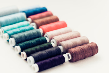 Colored sewing thread coils on white background with copy space for text.