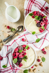 Two bowl with Semolina porridge with fresh berries, beige stone table copy space top view