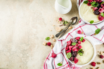 Two bowl with Semolina porridge with fresh berries, beige stone table copy space top view
