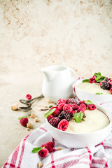 Two bowl with Semolina porridge with fresh berries, beige stone table copy space top view