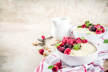 Two bowl with Semolina porridge with fresh berries, beige stone table copy space top view