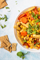 Curry with chickpea, turkey, carrot, leek and dried apricots in a white plate. Healthy food. Concrete background. Copy space.