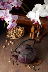 Oriental cast iron tea pot, pistachios, orchid flowers and decorative spices