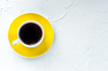 Yellow cup of coffee on a white background. Minimalism. Top view