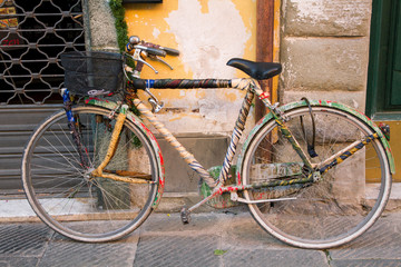 Fototapeta na wymiar Colorful old bicycle in the rustic style. Unusual and funny transport on the european street. Bike of an artist.
