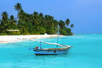 Naklejka na ściany i meble Paradise maldivian landscape with a traditional wooden sailboat, palm trees and the turquoise sea. Maldive islands (Maldives). 