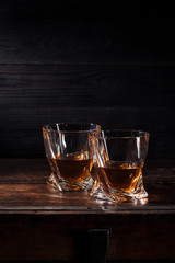 two glasses of whiskey on brown wooden table