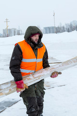 Worker in winter workwear with boards in his hands