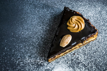 Piece of tasty chocolate cake with condensed milk and poppy, different layers. With almonds and cream. Home-made pastries. 