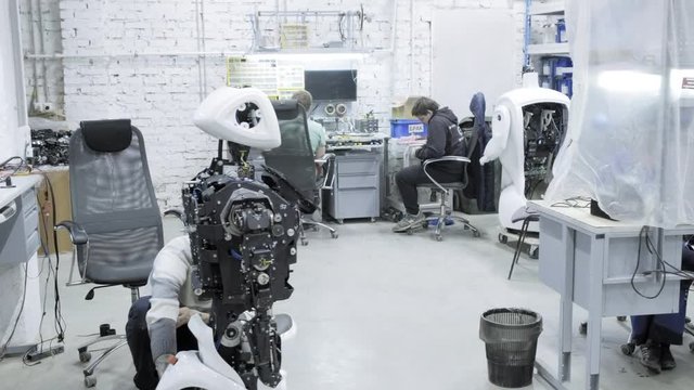 Factory for the production of robots, modern robotic developments. A group of young engineers creates new modern robots. Robots are disassembled in the shop.