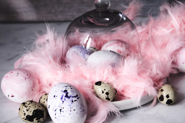 Easter background with Easter eggs and pink feathers. The view from the top. Quail egg